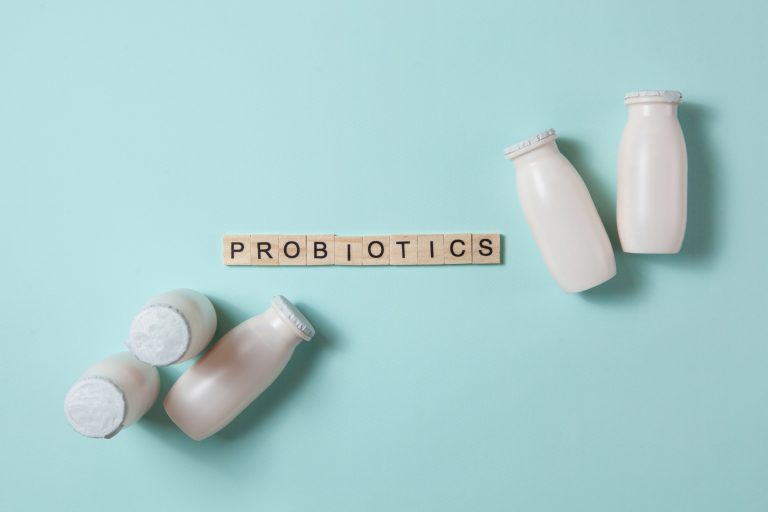 Bottles with probiotics and prebiotics dairy drink on light blue background.